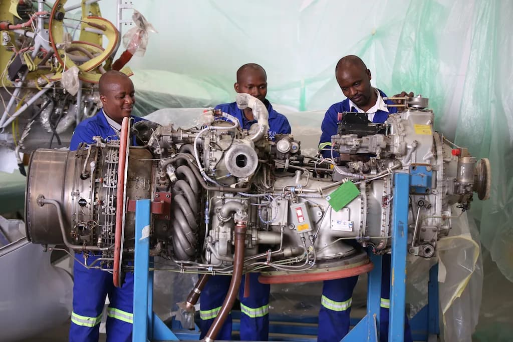 Three ALS engineers working on a turboprop engine on a stand in the ALS hangar.
