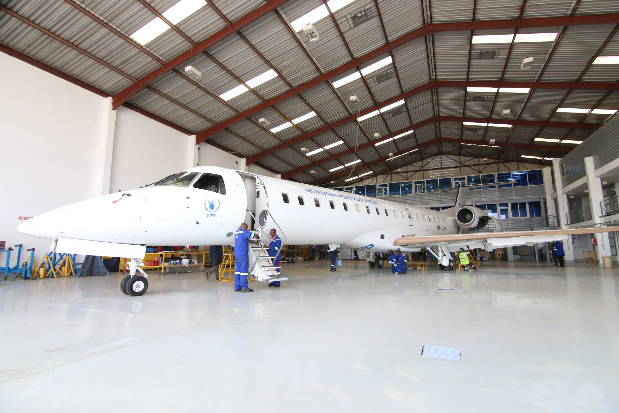 An ALS ERJ-145 in WFP colours in the ALS hangar, airstair down, engineers at work