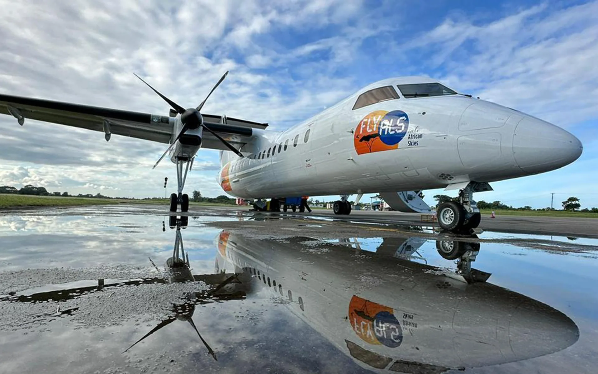 An ALS Dash 8 in Fly ALS colours reflected in a wet apron