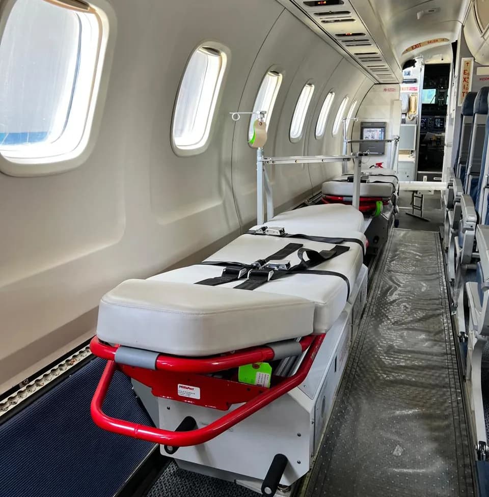A stretcher, drip stand and medical monitor in the cabin of an ALS Embraer air ambulance