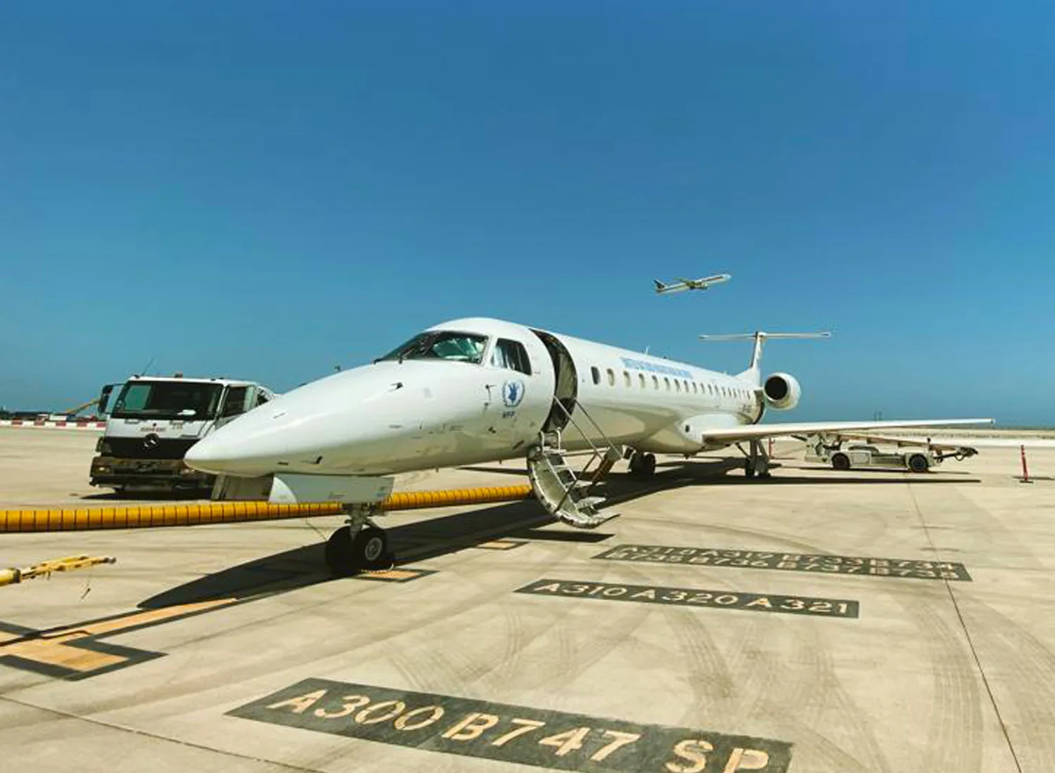 UNHAS Embraer ERJ-145 on a sunlit apron with its airstairs down and a fuel truck alongside