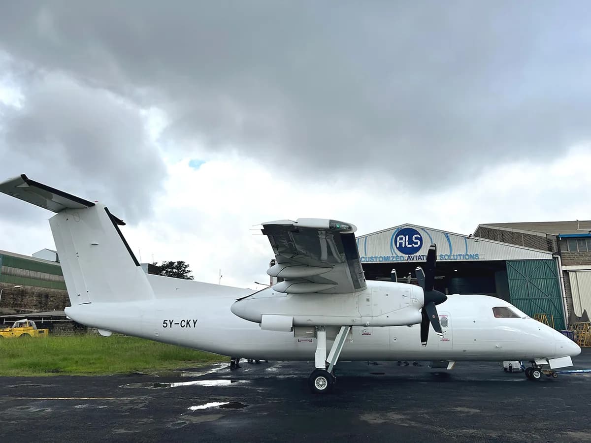 A white ALS Dash 8 outside the ALS hangar at Wilson Airport