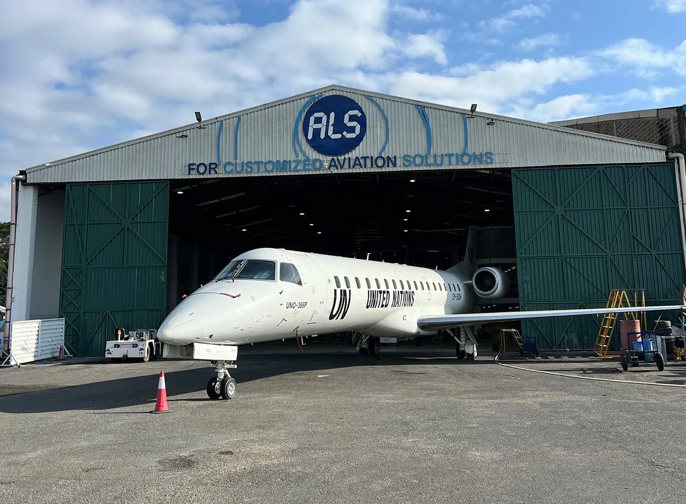 An Embraer ERJ-145 in United Nations titles in front of the ALS hangar